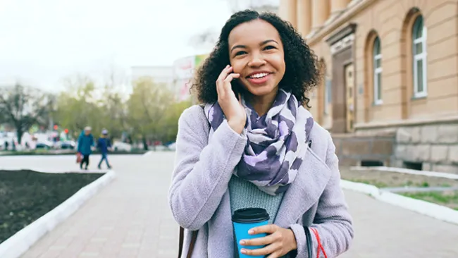 Happy woman walking and talking on a cellphone.