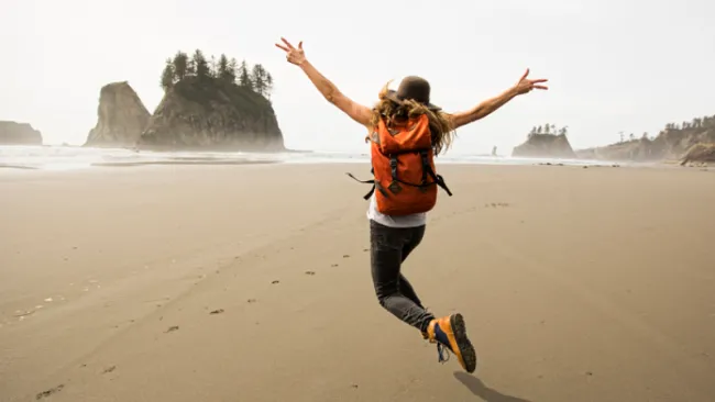 Woman with a backpack running along a beach